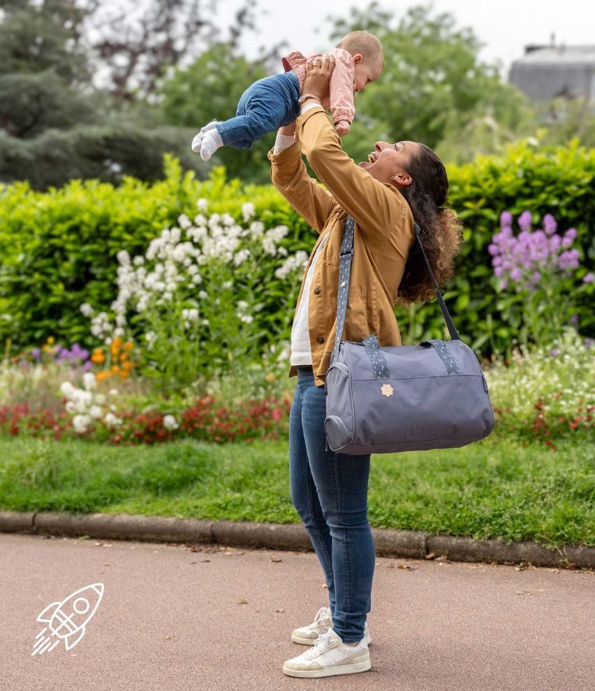 Maman portant le sac à langer Badabulle en balade au parc avec bébé