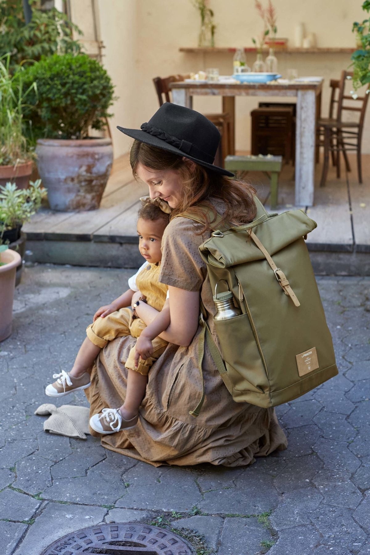 Maman portant le sac à dos à langer Lässig Rolltop olive avec son bébé