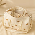 Sac à langer brodé animaux ouvert rempli d'affaires bébé (peluche, biberon, plaid)