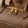 Sac à Langer Cuir Taupe : détail des zips dorés et du grain | BebeSac